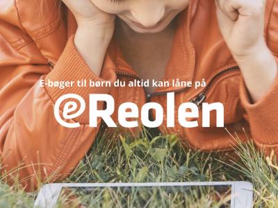 Børn læser en på en mobiltelefon, liggende i græsset